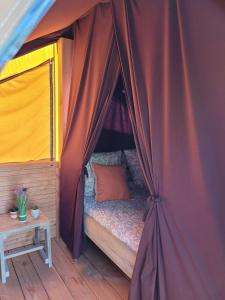 1 cama en una tienda con mesa en La CABANE PERCHÉE, en Saint-Valery-sur-Somme