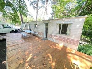 a deck with a trailer with a table and a bench at Your Camp Kormoran Domek Holender in Hel