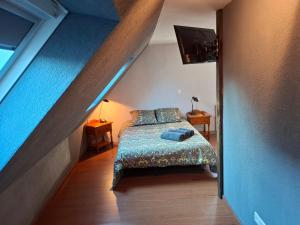a bedroom with a bed with a blue bedspread in a attic at Chambre d'hotes au coeur du village in Reichshoffen
