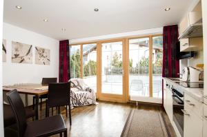 a kitchen with a table and a dining room with a view of a patio at Ambiente Appartements in Ischgl