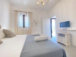 a white bedroom with a large bed and a television at Symphony Sound Villa with Pool in Chiesanuova
