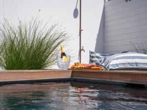 a table with fruit and a bottle of wine next to a pool at Studio 56 in Langebaan