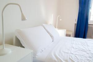 a white bed with white sheets and a blue curtain at Padova Umberto center appartments in Padova