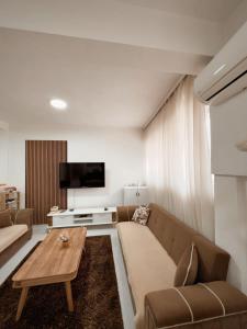 uma sala de estar com um sofá e uma mesa em Cozy Corner Apartment em Gjakove