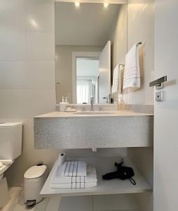 Un baño con lavabo, inodoro y espejo. en Apto charmoso Gleba Palhano, en Londrina