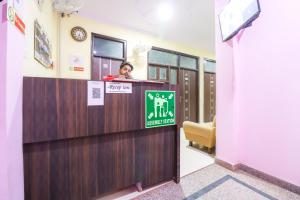 une femme debout à un bureau de réception dans une pièce dans l'établissement Hotel O Sunrise Inn, à Indirapuram
