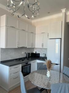 eine Küche mit weißen Schränken und einem Tisch mit Stühlen in der Unterkunft Premium Plaza in Aqtau