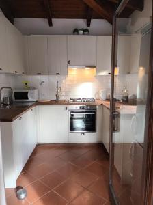 a kitchen with white cabinets and a stove top oven at Villa Déborah in Cuile Pazzoni