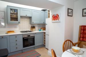 a kitchen with blue cabinets and a white refrigerator at Y Bwthyn Newport, Pembrokeshire in Newport Pembrokeshire