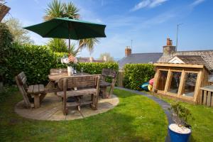 a table and chairs with an umbrella in a garden at Y Bwthyn Newport, Pembrokeshire in Newport Pembrokeshire