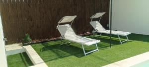 zwei Stühle auf dem Gras neben einem Zaun in der Unterkunft L'Orée des Alpilles Proche Centre ville St Rémy de Provence in Saint-Rémy-de-Provence