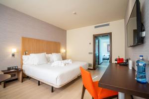 a hotel room with a bed and a desk and a table at Abba Huesca in Huesca +27 photos