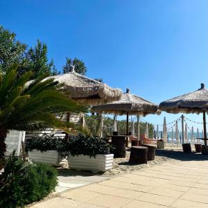 a group of tables and straw umbrellas on the beach at Vera Hotel in Porto San Giorgio