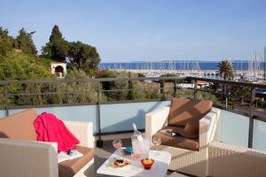 een balkon met stoelen en een tafel met wijnglazen bij Hôtel Baptistin in Le Lavandou