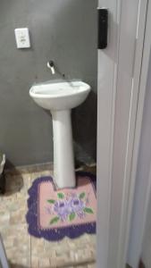 a bathroom with a white sink and a rug on the floor at Kitnete canto verde in Ponta Grossa