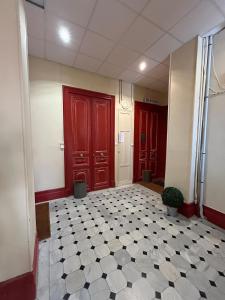 a hallway with red doors and a black and white tile floor at Studio 50m de la mer in Menton