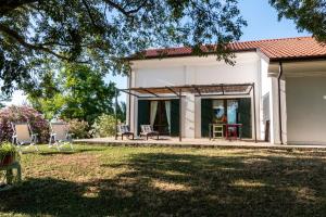 a white house with chairs and a yard at all'ombra del Bagolaro in Taglio di Po
