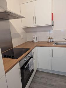 ニューカッスル・アポン・タインにある3 Bed Executive Apartmentの白いキャビネットとコンロ付きオーブンを備えたキッチン