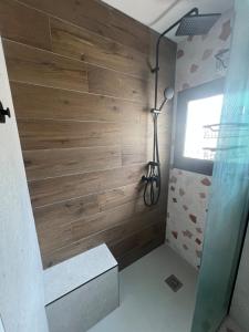 a bathroom with a shower with a wooden wall at Maison Terracotta des Karantes in Narbonne-Plage