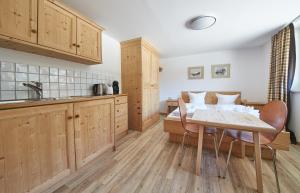 a kitchen with wooden cabinets and a table and chairs at Appartement Kohlmais in Saalbach Hinterglemm