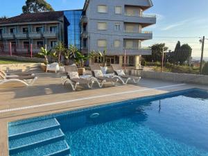 a pool with chairs and a building in the background at LA DESEADA 6 Personas in Soutullo