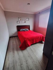 ein Schlafzimmer mit einem roten Bett mit einer roten Decke in der Unterkunft Hermosa Casa Vacacional o de Hospedaje en Cuenca in Cuenca