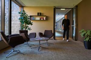 a man walking down a hallway with chairs and a table at Sternen Hotel Wolfurt in Bregenz