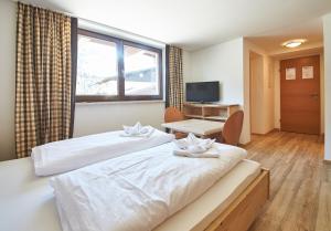 a hotel room with two beds and a desk at Appartement Kohlmais in Saalbach Hinterglemm