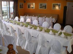 un largo salón de banquetes con mesas blancas y sillas blancas en Gasthaus Stobbermühle, en Buckow