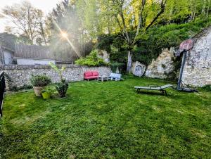 a yard with a stone wall and a bench at Au fil de la Cisse in Molineuf