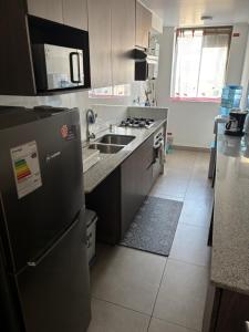 a kitchen with a black refrigerator and a sink at Hermoso departamento in Iquique +1 photo