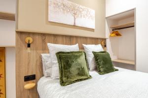 a bedroom with a white bed with green pillows at Studio Luxe & Confort - Elegance Coeur de Béziers in Béziers