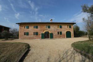 una vieja casa de ladrillo con puertas verdes en un campo en La Barchessa Country House en Budrio