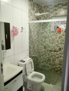 a bathroom with a toilet and a glass shower at Família munhoz in Cananéia