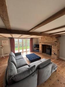 ein Wohnzimmer mit Couch und Kamin in der Unterkunft Bakers Cottage, Blackmore End in Gosfield