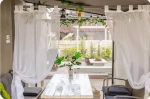 a table and chairs in front of a window with curtains at All in one Guesthouse in Incheon