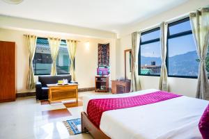 甘托克Sparrow Juniper Tree 2 min walk To Mg Marg的一间卧室，里面有一张床、一把椅子和几扇窗户。