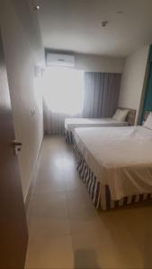 two beds in a hotel room with a window at Apto em Olímpia- Enjoy Solar das Águas Park Resort in Olímpia