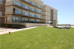 Un gran edificio con un césped verde delante. en Sea View by CELTIS, en Cariló