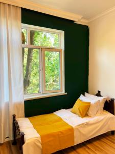 a bedroom with a bed with a green wall and a window at Soft Villa in Gabala