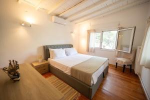 a bedroom with a bed and a chair and a window at Αeraki Villa at Heraion Lagoon in Loutraki