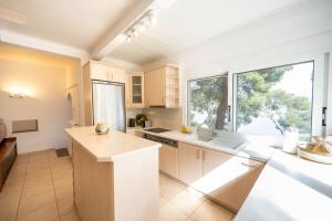 a kitchen with white cabinets and a large window at Αeraki Villa at Heraion Lagoon in Loutraki