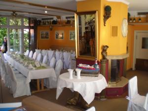 Habitación con mesas blancas, sillas blancas y espejo. en Gasthaus Stobbermühle, en Buckow