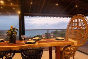 a wooden table with chairs and wine glasses in front of a window at Casa Amar Pipa in Pipa