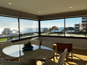 a dining room with a table and chairs and windows at FLH Cascais Atrium Luxury Apartment with Sea View and Pool in Cascais