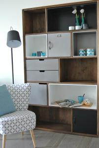 a large wooden entertainment center with white drawers and a chair at Lo-Gies in Lochristi