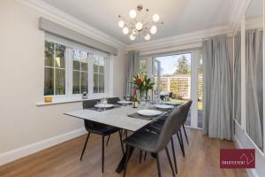 a dining room with a table and chairs and windows at Maidenhead - 4 bedroom house - garden and parking in Maidenhead