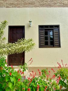 two windows on a building with red flowers in front at Sítio Barra - Suíte Privada Independente 1 in Guaramiranga