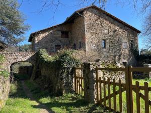 an old stone house with a wooden fence at Camping La Charderie in Pont-de-Labeaume
