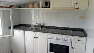 a white kitchen with a sink and a stove at Apartamento Planeta 2º centro in O Porto de Espasante +3 photos